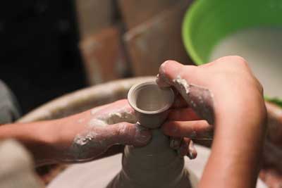 Photo of working with clay on a pottery wheel.