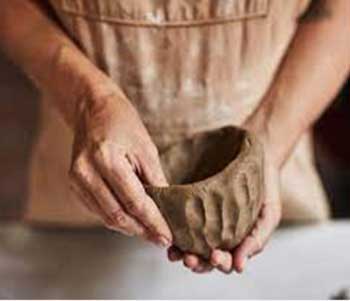 Close-up of hands forming a pot from clay.
